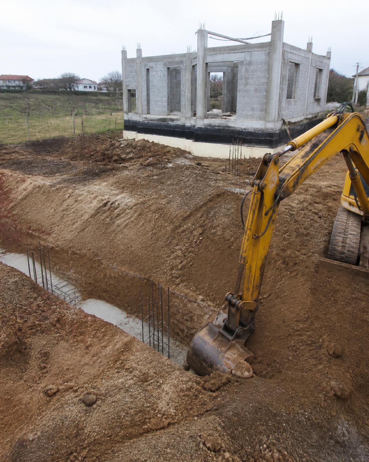 Escavadora a abrir fundações numa moradia contemporânea em construção